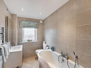 A modern bathroom with a bathtub, toilet, sink, and window with a decorative valance. - 3 Bed in Seahouses (oc-cn094) (Seahouses)