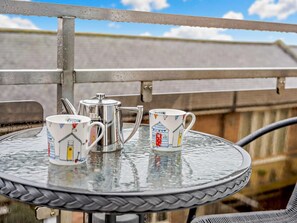 A metal table with a glass top, a metal coffee pot, and two ceramic mugs with illustrations. - 3 Bed in Seahouses (oc-cn094) (Seahouses)
