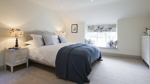 Ein Schlafzimmer mit Bett, Nachttisch, Lampe, Fenster und Kommode.