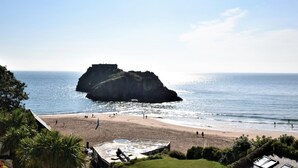 Blick auf die Küste mit einer markanten Felsformation, einem Strand und einem Gebäude mit flachem Dach.