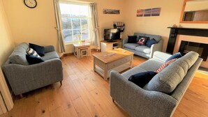 Ein Wohnzimmer mit zwei grauen Sofas, einem Couchtisch, einem Fernseher und einem Kamin.