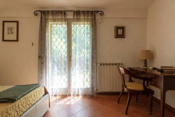 A bedroom with a bed, a desk, a chair, and a radiator.