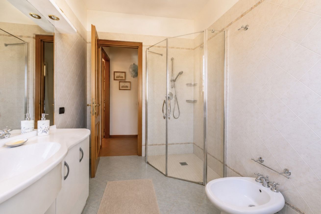 A bathroom with a glass-enclosed shower, a sink, and a mirror.