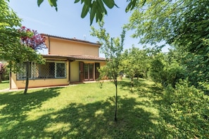 A house with a fenced yard, a small tree, and a clear sky.