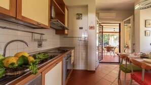 Een keuken met houten kasten, een roestvrijstalen spoelbak en een eethoek met een tafel en stoelen.