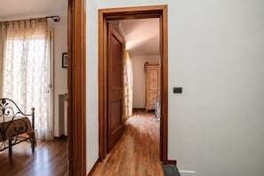 A wooden door leading to a hallway with a bed and a cabinet.