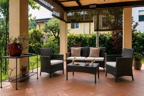 An outdoor patio with wicker furniture, a table, and potted plants.