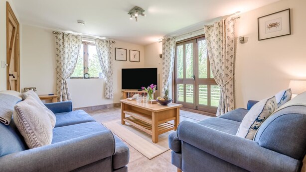 A living room with two sofas, a coffee table, a flat-screen TV, and large windows with curtains. - 2 Bed in Bude (oc-wooww) (Poundstock)