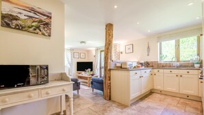 A kitchen with a dining area, a TV, and a painting on the wall. - 2 Bed in Bude (oc-wooww) (Poundstock)