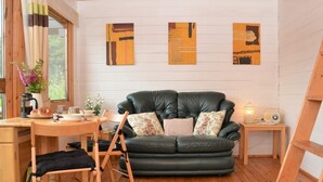 Una habitación acogedora con un sofá de cuero verde, suelo de madera y una mesita con una lámpara y radio.