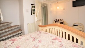 A bedroom with a bed, a chair, a TV, and a staircase. - 1 Bed in Par- (oc-sybar) (Saint Blazey)