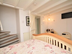 Ein Schlafzimmer mit Bett, einem Sessel, einem Fernseher und einer Treppe.