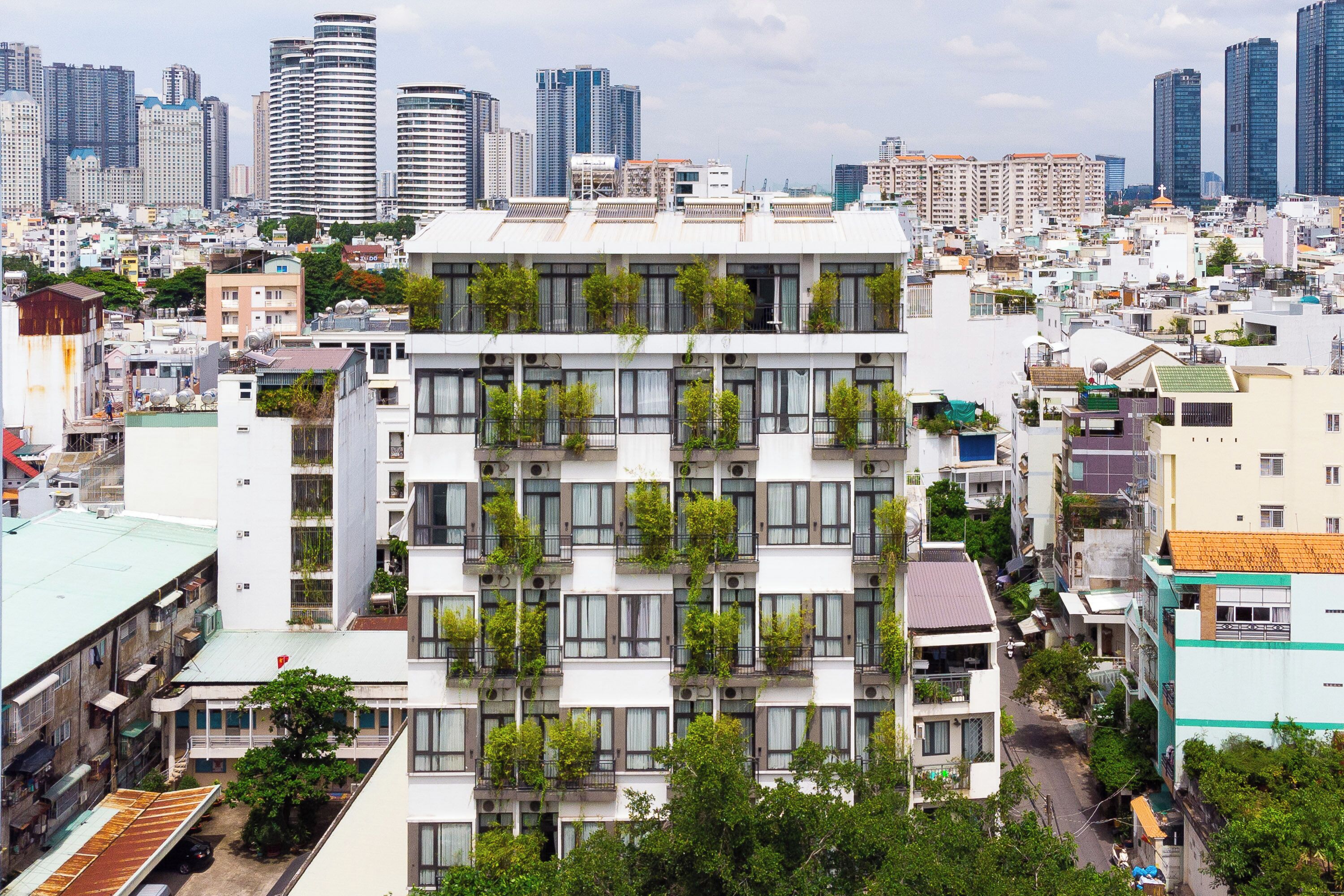 A multi-story building with balconies, surrounded by other buildings and a city skyline.