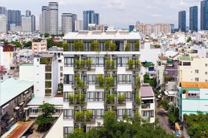 Edifici d'amb diversos pisos amb balcons, envoltat d'altres edificis i un perfil urbà.