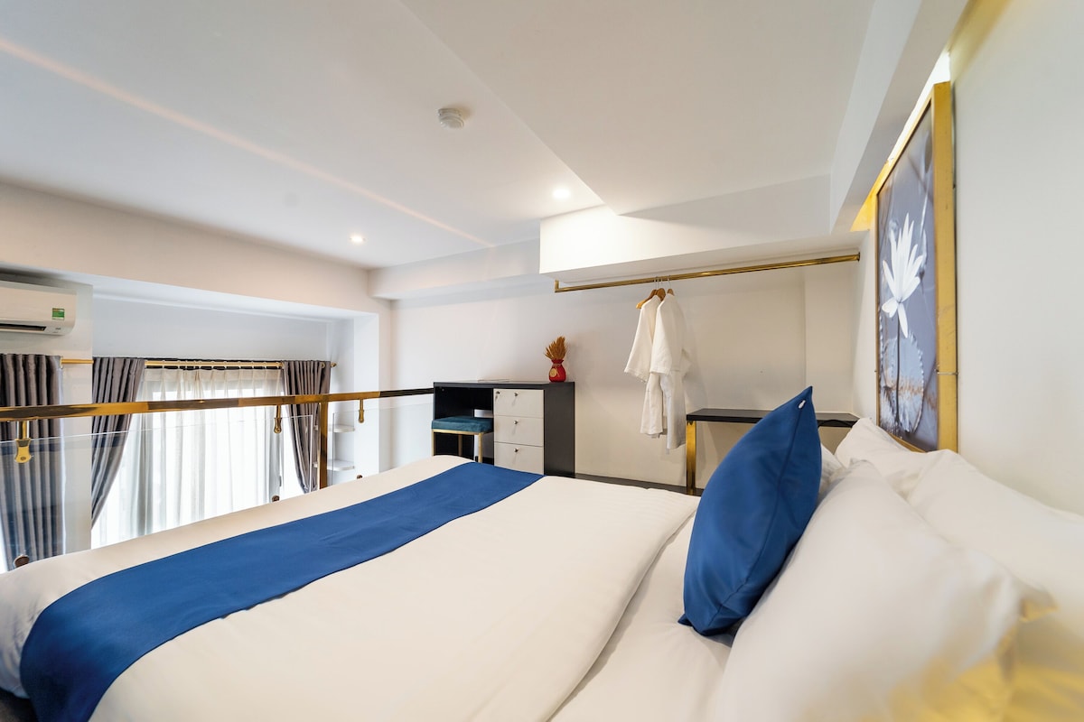 Ein Hotelzimmer mit einem Bett, einem Schreibtisch, einem Stuhl und einem fensterbepflanzten Fenster.