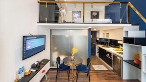 A modern kitchen with a dining area, a TV, and a staircase leading to an upper level. - Home Park Hotel HCM (Ho Chi Minh City)