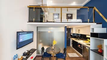 Eine moderne Küche mit Essbereich, einem Fernseher und einer Treppe zu einer oberen Etage.