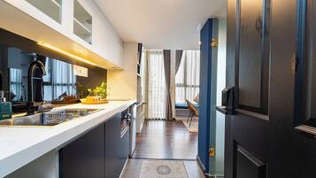 A modern kitchen with a central island, a dining area with a chair, and a view through a doorway.