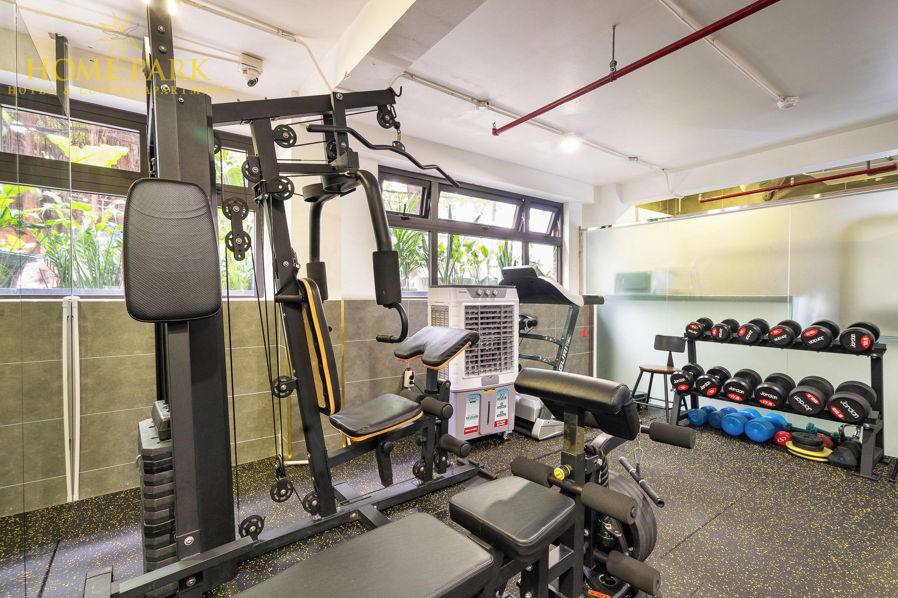 Een sportschool met fitnessapparatuur, een bank en een rek met gewichten.