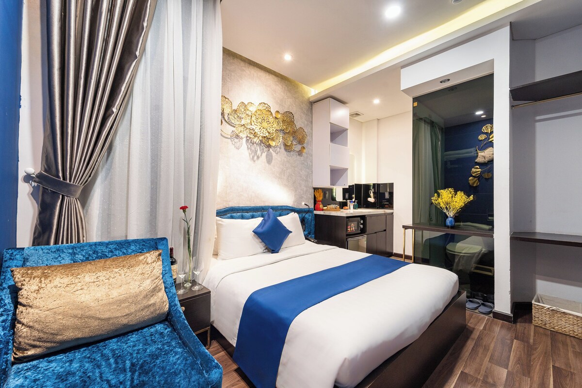 Een moderne hotelkamer met een groot bed, een zithoek, een kitchenette en een badkamer.