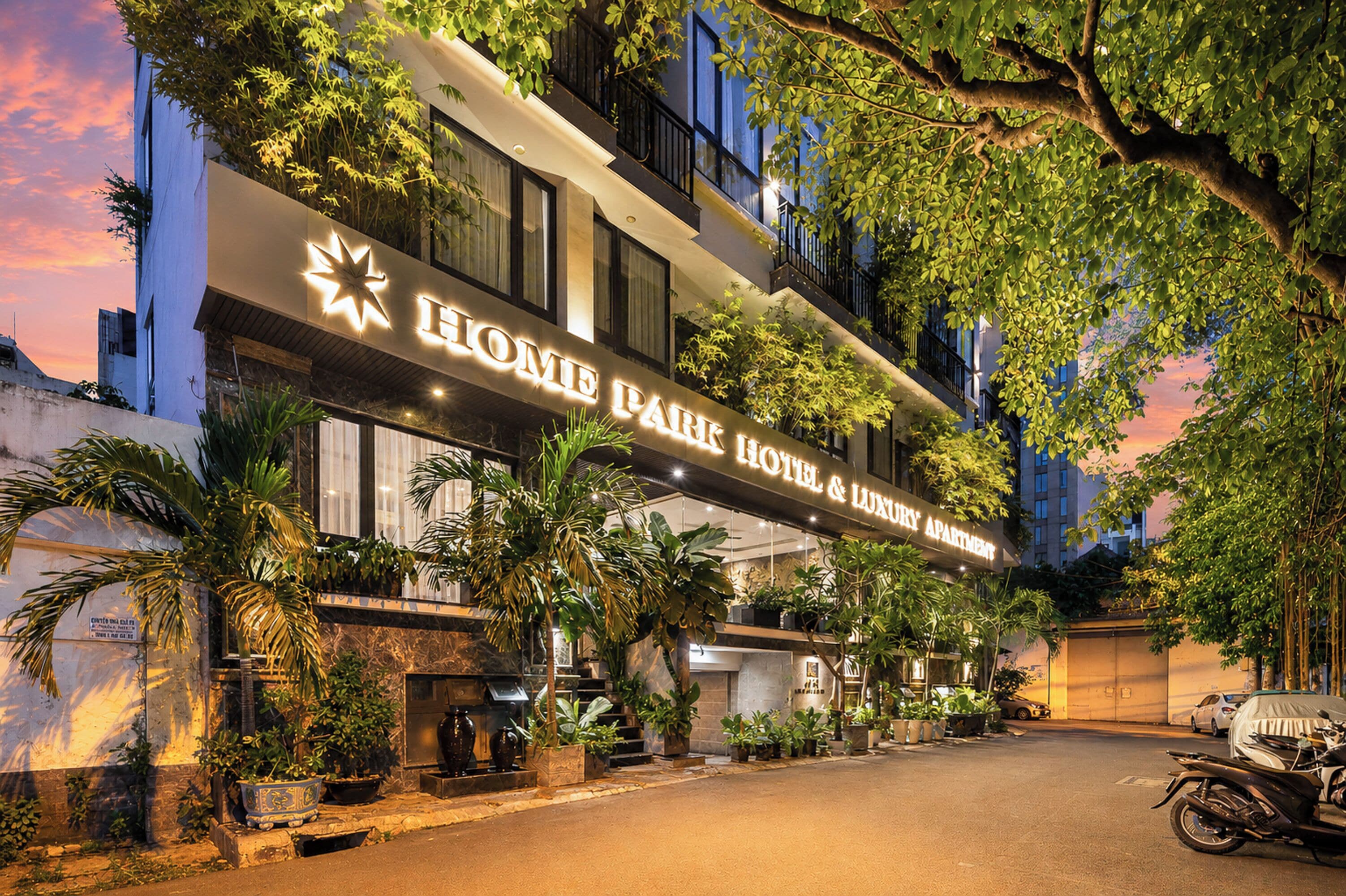 Un hôtel avec une enseigne indiquant « HOME PARK HOTEL & APPARTEMENTS DE LUXE » et un parking couvert.