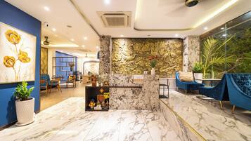 Een hotel lobby met marmeren vloeren, blauwe wanden en een receptiebalie.