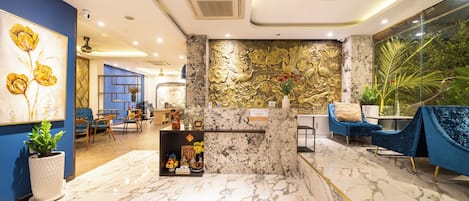 A hotel lobby with marble flooring, blue walls, and a reception desk.