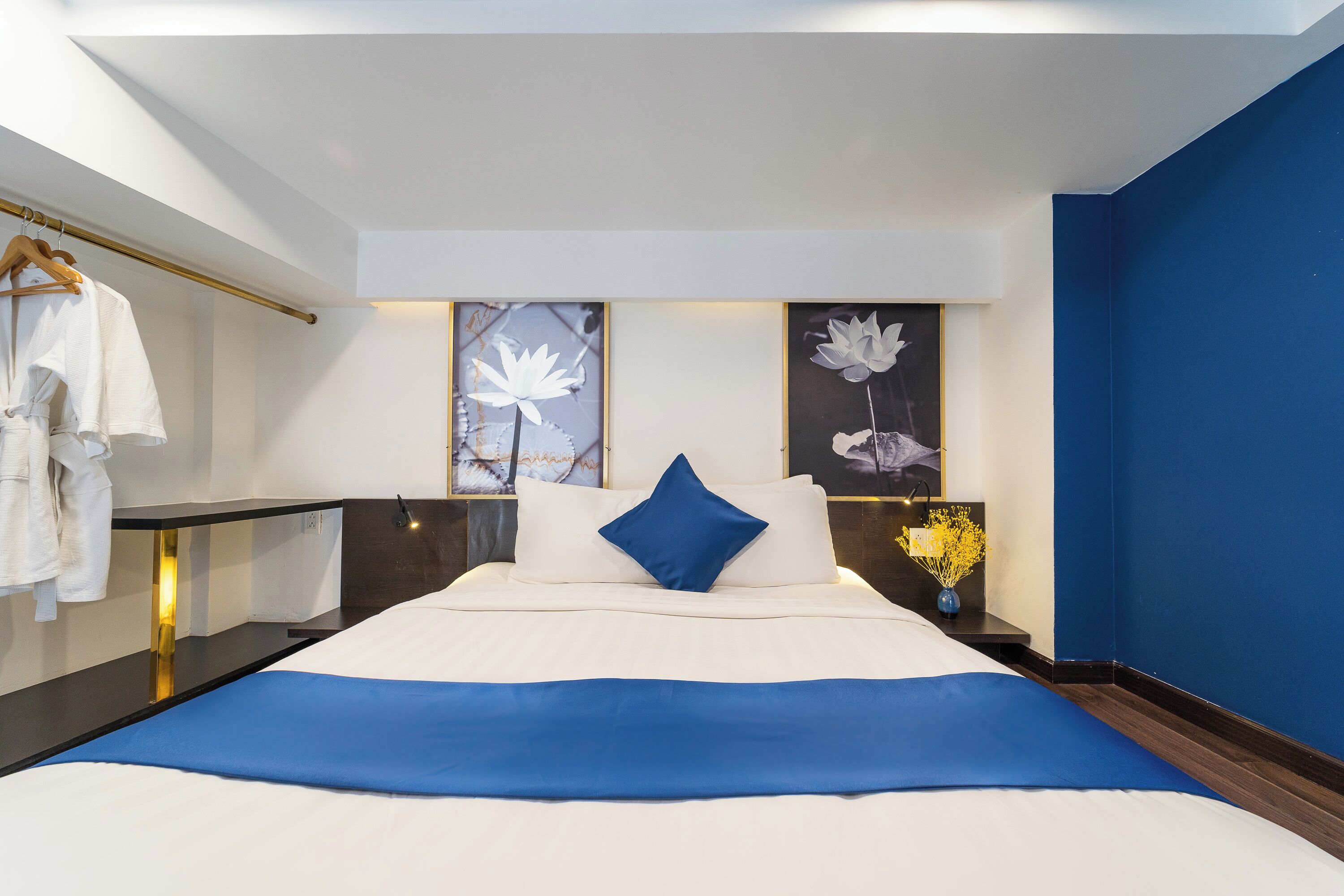 Una habitación de hotel moderna con una cama grande, una mesita de noche, un armario y obras de arte en las paredes.