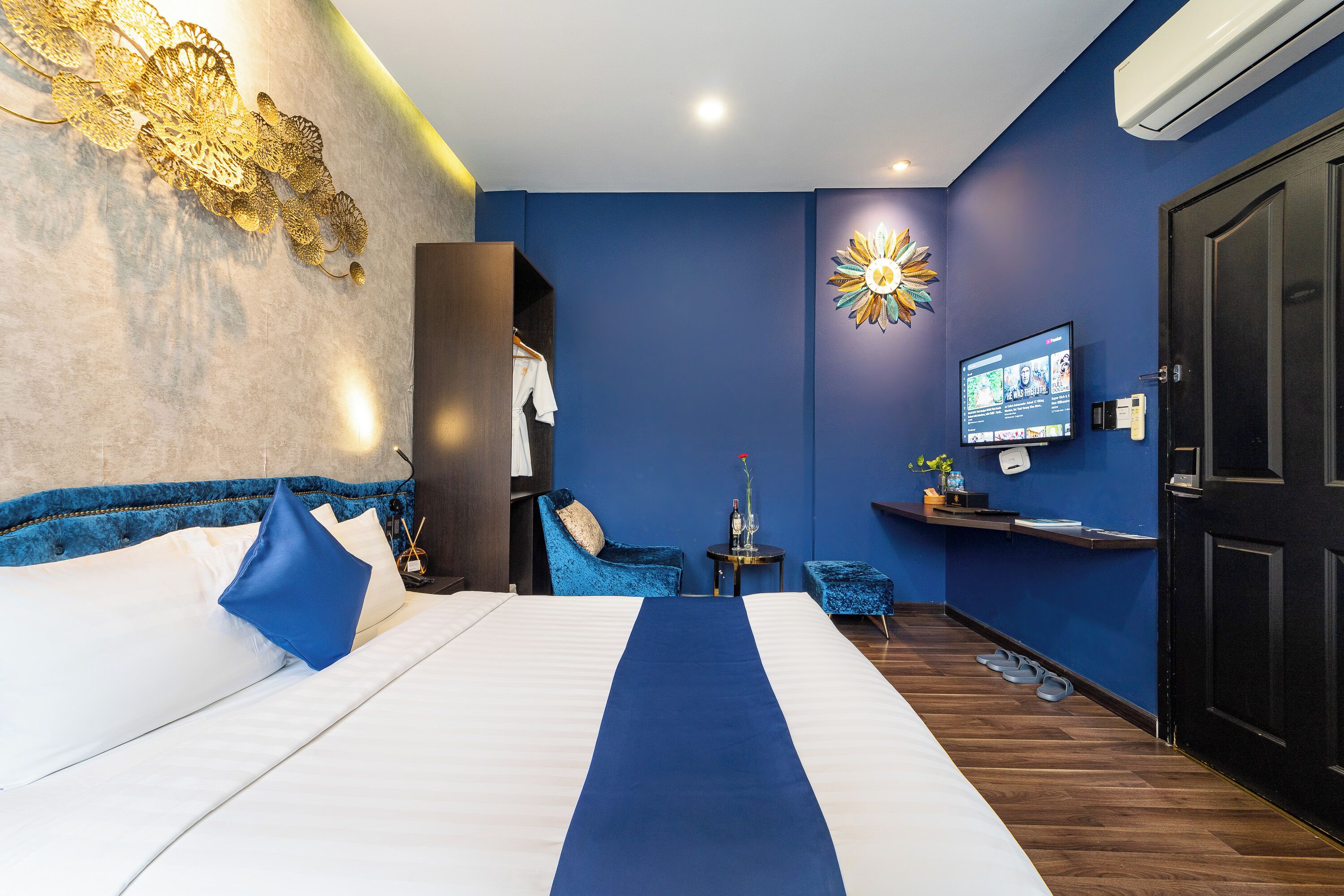 A hotel room with a bed, a TV, a desk, a chair, and a wardrobe.