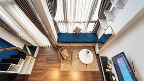 A modern room with a blue sofa, a round coffee table, a wicker chair, and a staircase with black and white steps. - Home Park Hotel HCM (Ho Chi Minh City)