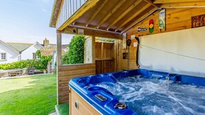Ein Holz-Hot-Tub mit einer Holzterrasse, ein Schild mit einer Beschilderung und ein Haus im Hintergrund.