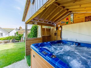 Ein Holz-Hot-Tub mit einer Holzterrasse, ein Schild mit einer Beschilderung und ein Haus im Hintergrund.
