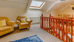 Ein Dachzimmer mit einem Oberlicht, einer Holztreppe und einem Essbereich.