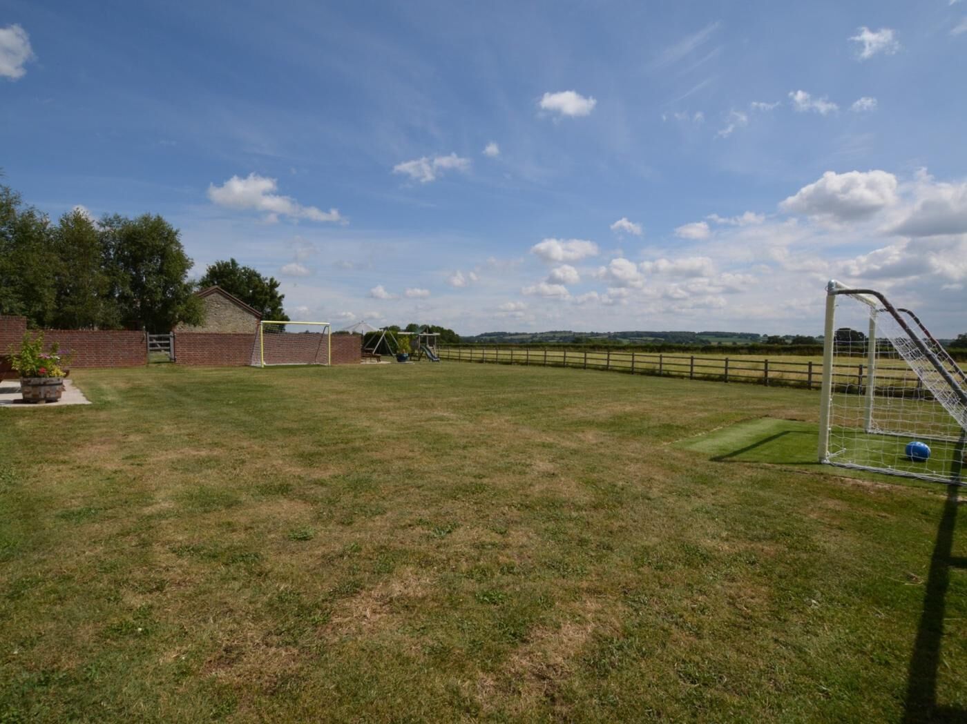 A grassy field with a goalpost and a brick building.