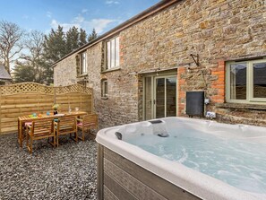 A stone building with a hot tub, wooden table, and chairs outside. - 3 Bed in Beaworthy (oc-wvfco) (Ashwater)