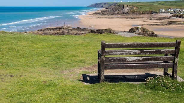 A bench overlooking a beach with the ocean and hills in the background. - 3 Bed in Beaworthy (oc-wvfco) (Ashwater)