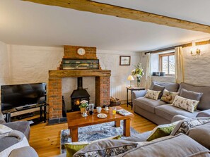 A cozy living room with a brick fireplace, a television, a sofa, and a coffee table. - 3 Bed in Beaworthy (oc-wvfco) (Ashwater)
