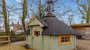 A small wooden cabin with a hexagonal window, a door, and a chimney. - 3 Bed in Beaworthy (oc-wvfco) (Ashwater)