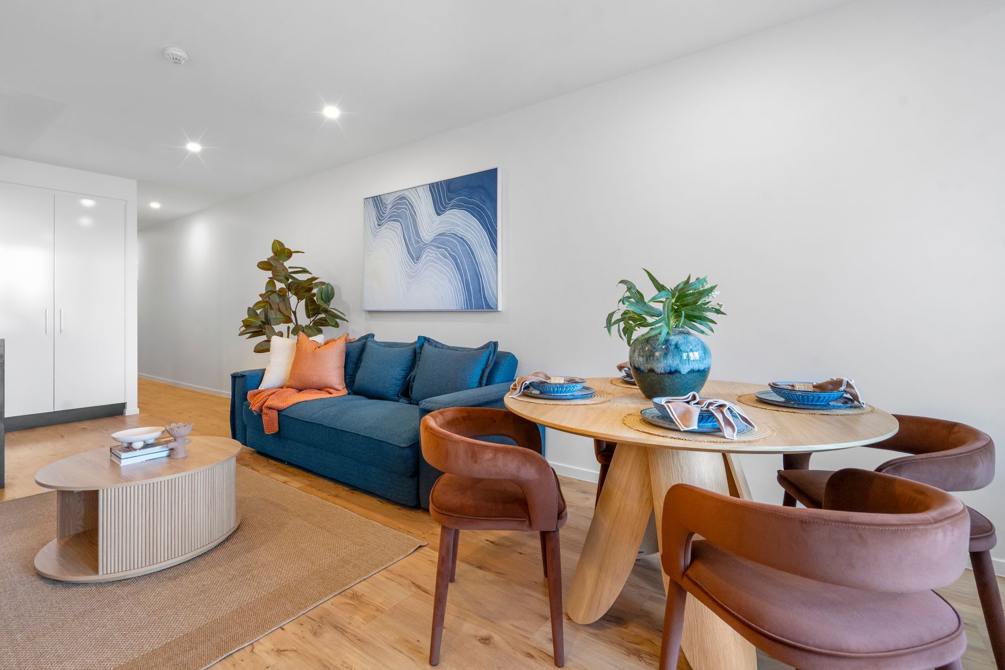 A modern living room with a sofa, coffee table, and dining area with chairs and a table.
