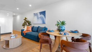 A modern living room with a sofa, coffee table, and dining area with chairs and a table.