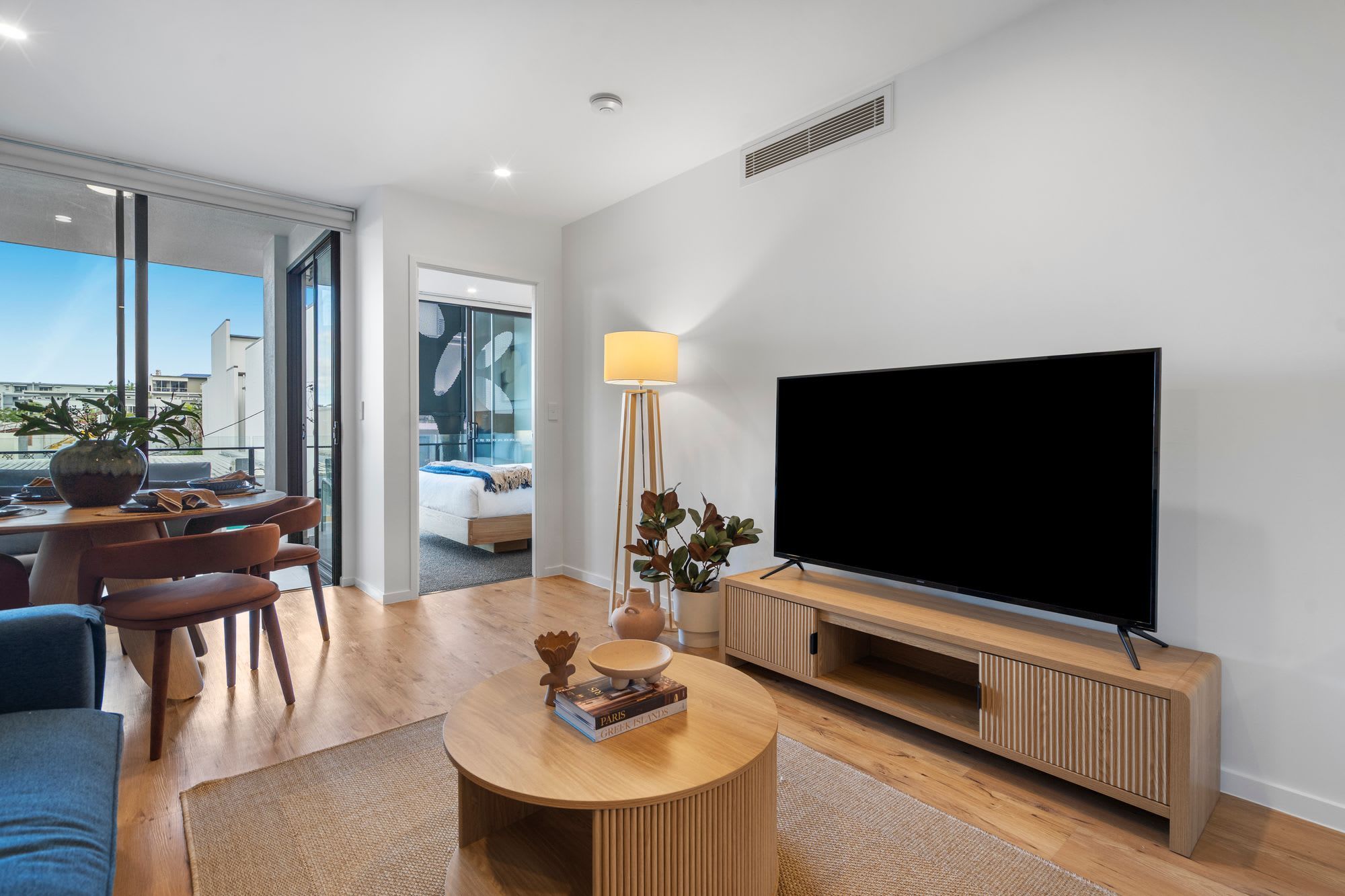 A modern living room with a flat-screen TV, a round coffee table, and a sofa.