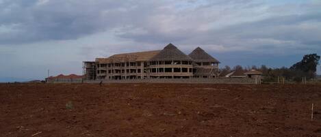 A large building with a flat roof and multiple levels, surrounded by a barren landscape.