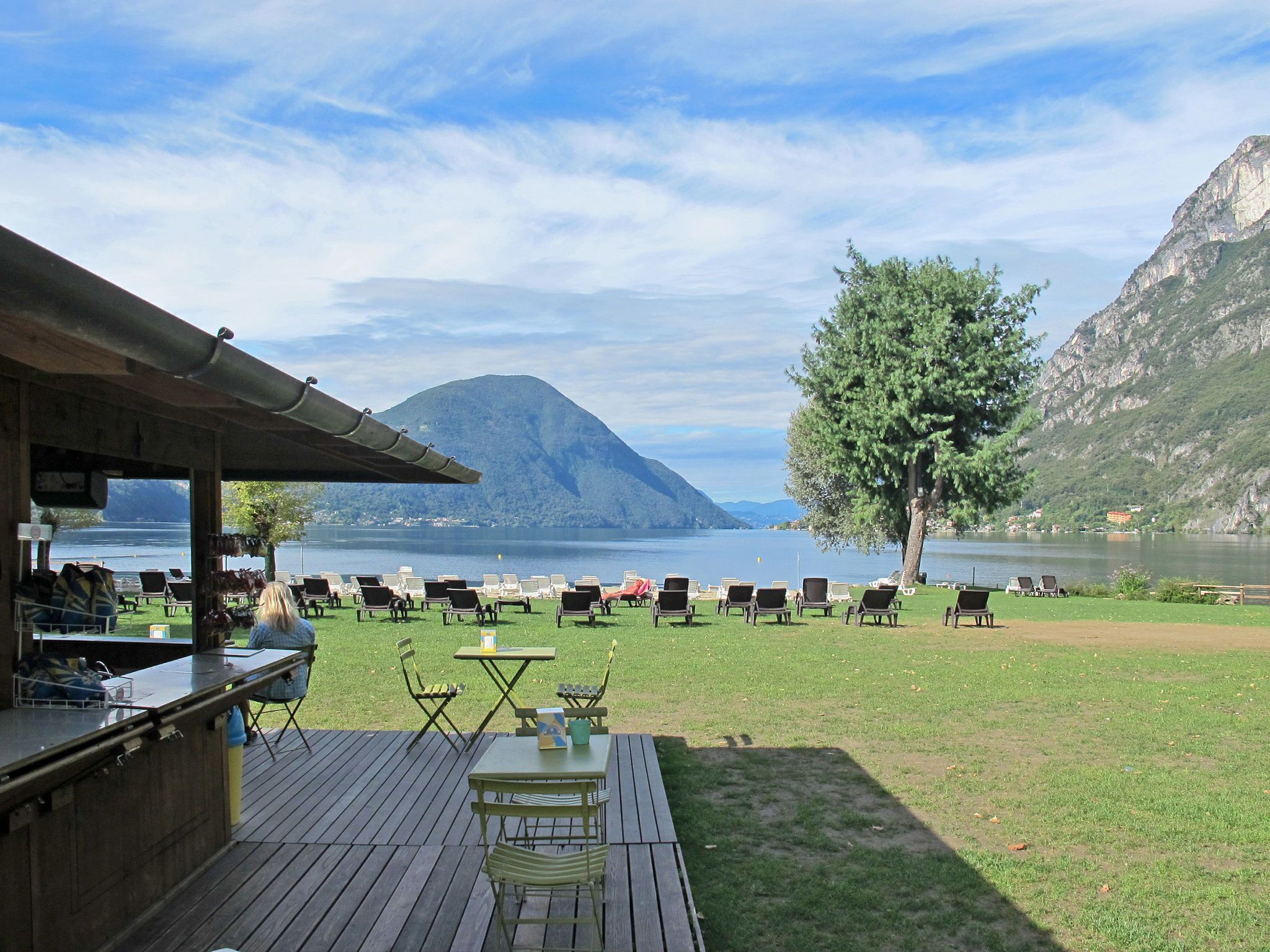 A deck with outdoor seating and a view of a lake and mountains.
