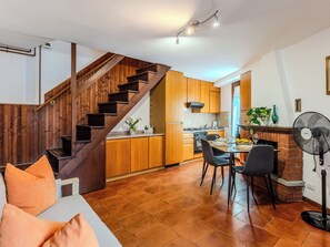 Una cocina moderna con armarios de madera, un comedor con mesa y sillas, y una escalera.
