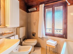 Baño con inodoro, lavamanos y cabina de ducha.