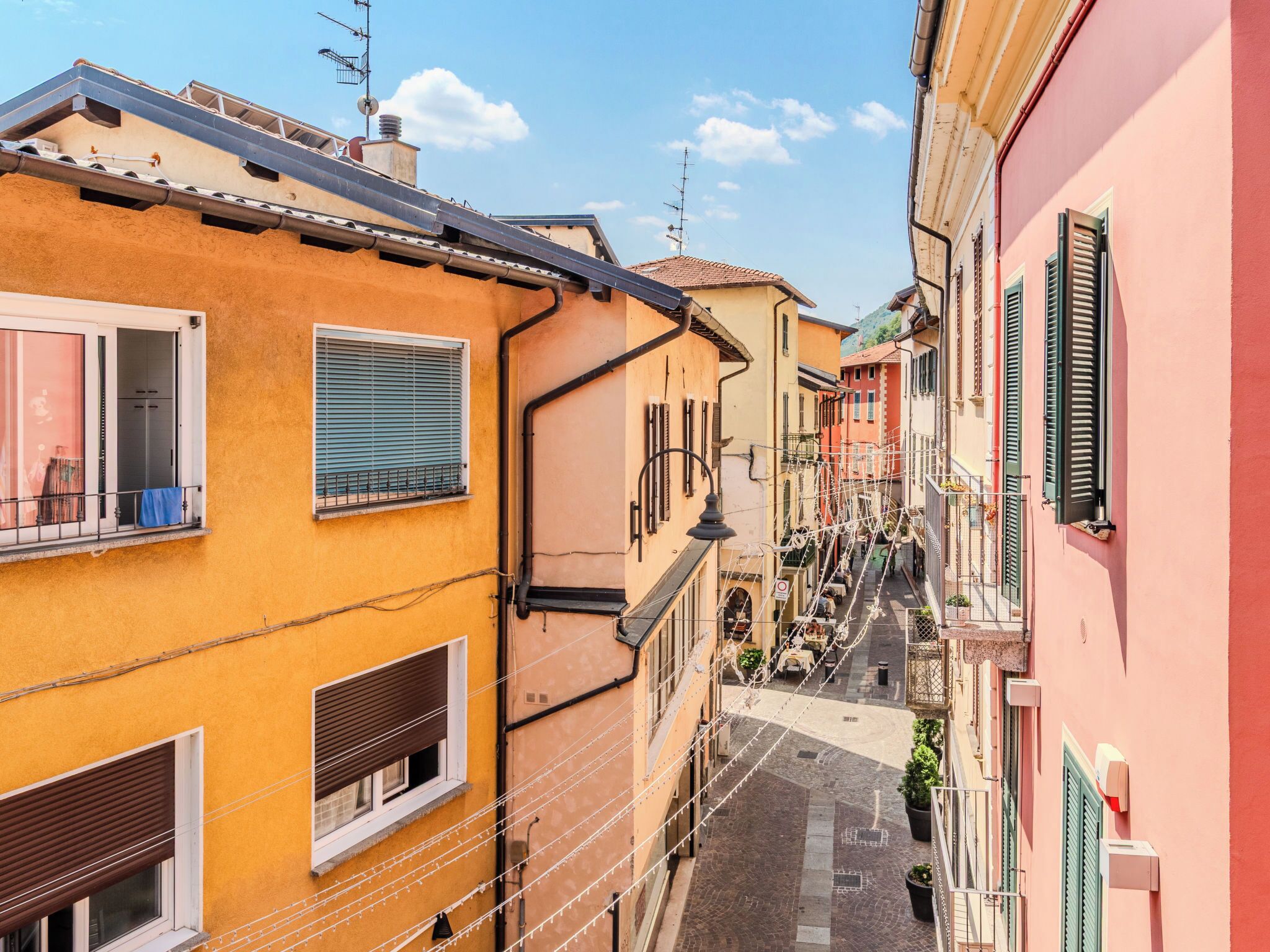 Une rue étroite, bordée de bâtiments des deux côtés, avec des balcons et des fenêtres.