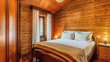 A wooden-paneled bedroom with a bed, nightstands, and a window with curtains.