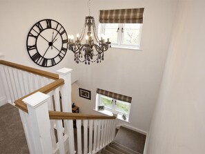 A staircase with a white railing, a large wall clock, a chandelier, and windows with plaid valances. - 4 Bed in Rosedale Abbey (oc-g0074) (Rosedale West Side)
