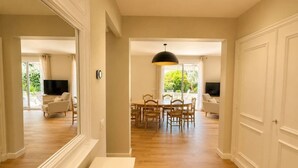 Une pièce spacieuse avec un plancher en bois, un coin repas comprenant une table et des chaises, et un grand miroir accroché au mur.