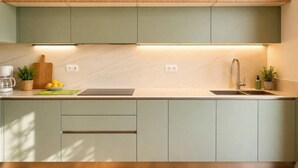 Une cuisine moderne avec des meubles de couleur vert clair, un plan de travail en bois, un évier et une machine à café.
